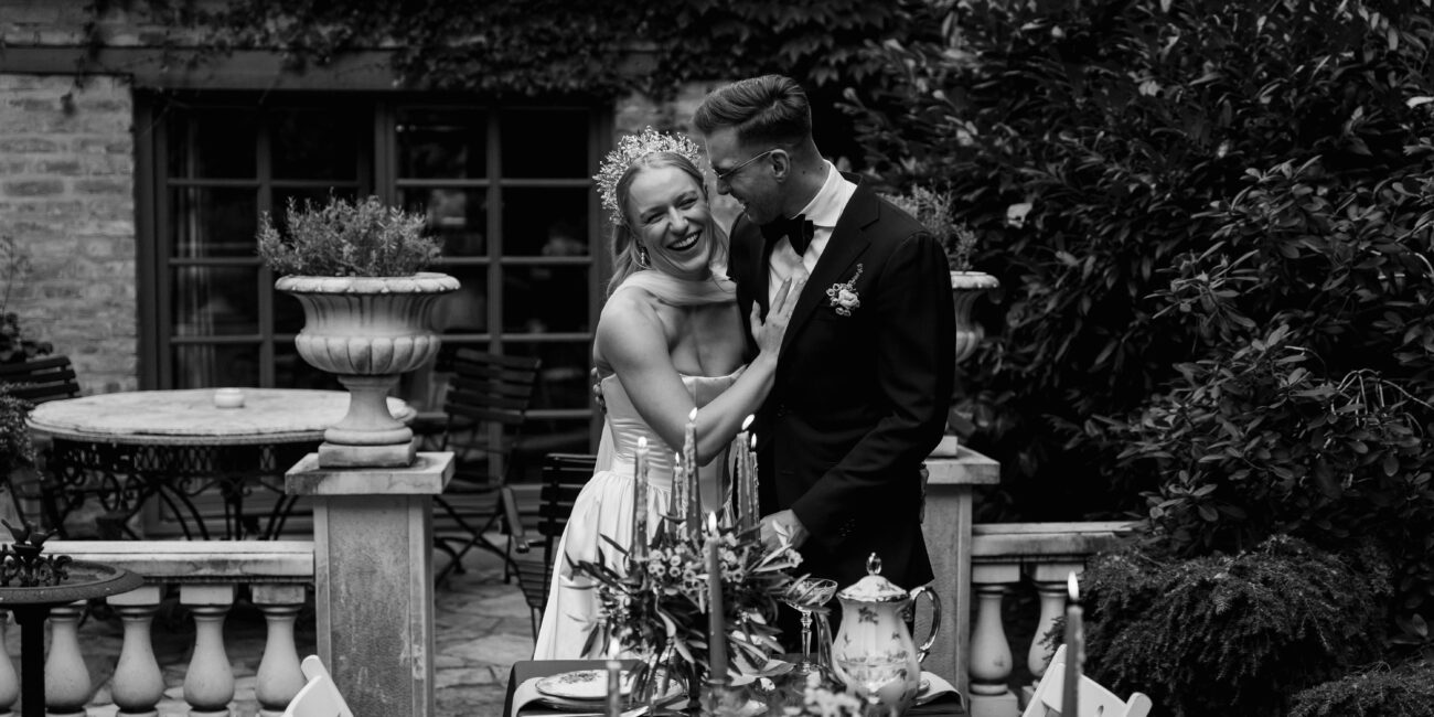 Black white picture of a newlywed couple looking at their whimsical dinner table in a garden in Berlin