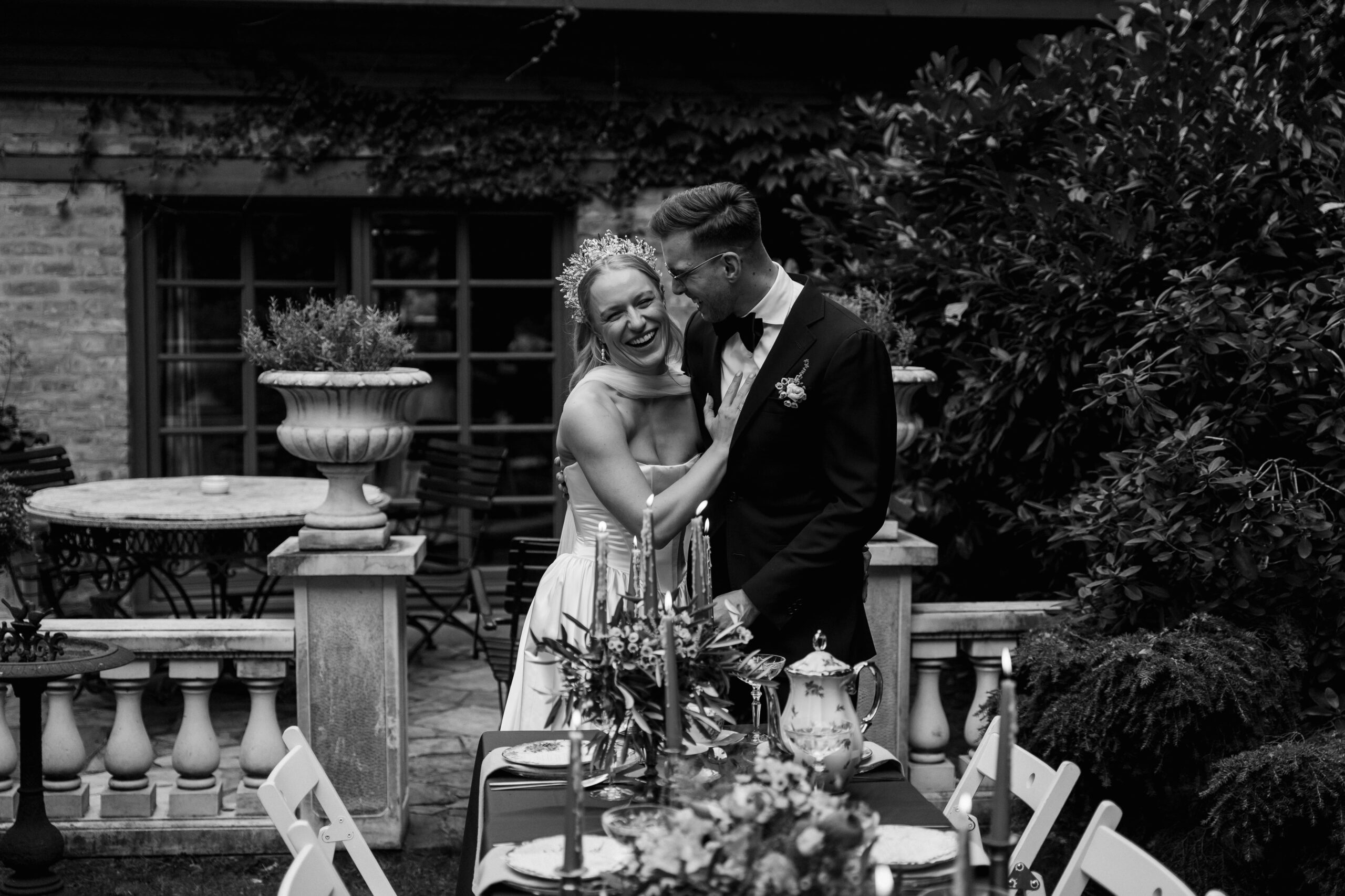 Black white picture of a newlywed couple looking at their whimsical dinner table in a garden in Berlin